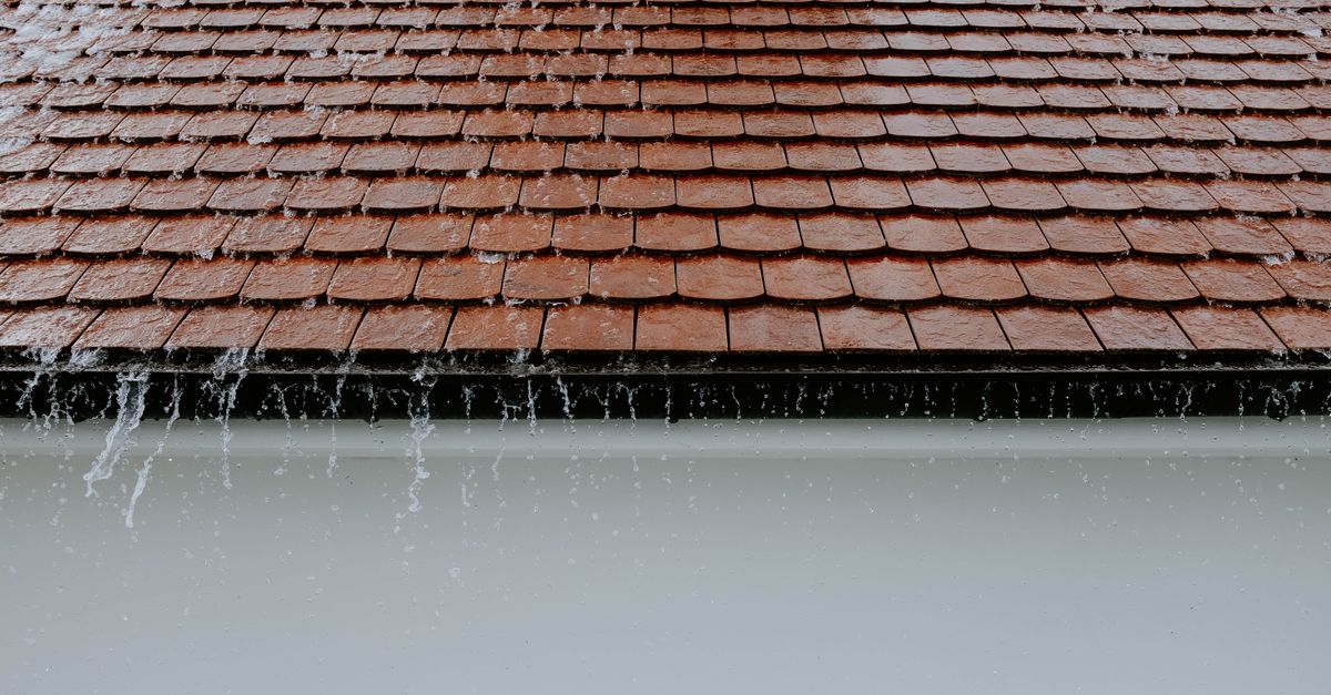 Brown roof tiles with rainwater cascading down, showcasing architectural texture and detail.